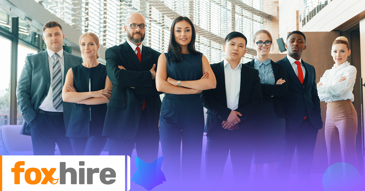 Group of professionals standing together in an office setting with the 'foxhire' logo in the foreground