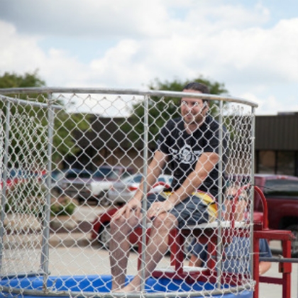 Person sitting on a dunk tank platform in an outdoor setting