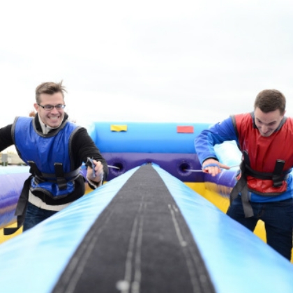 Two people wearing harnesses engaged in a bungee run activity
