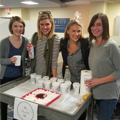 Four people standing around a hot chocolate bar setup