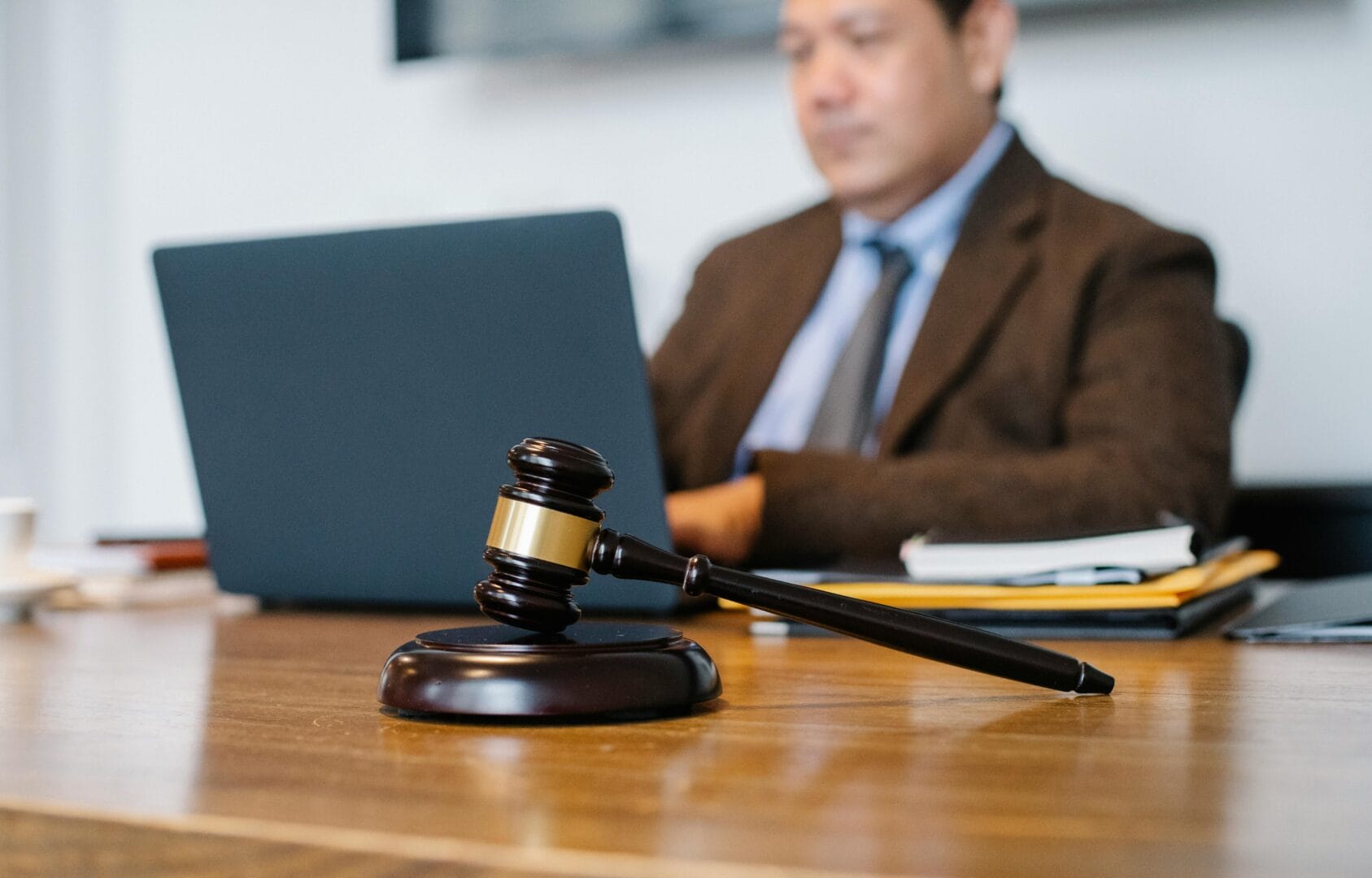 Gavel on a desk with a blurred background of a person in a suit.