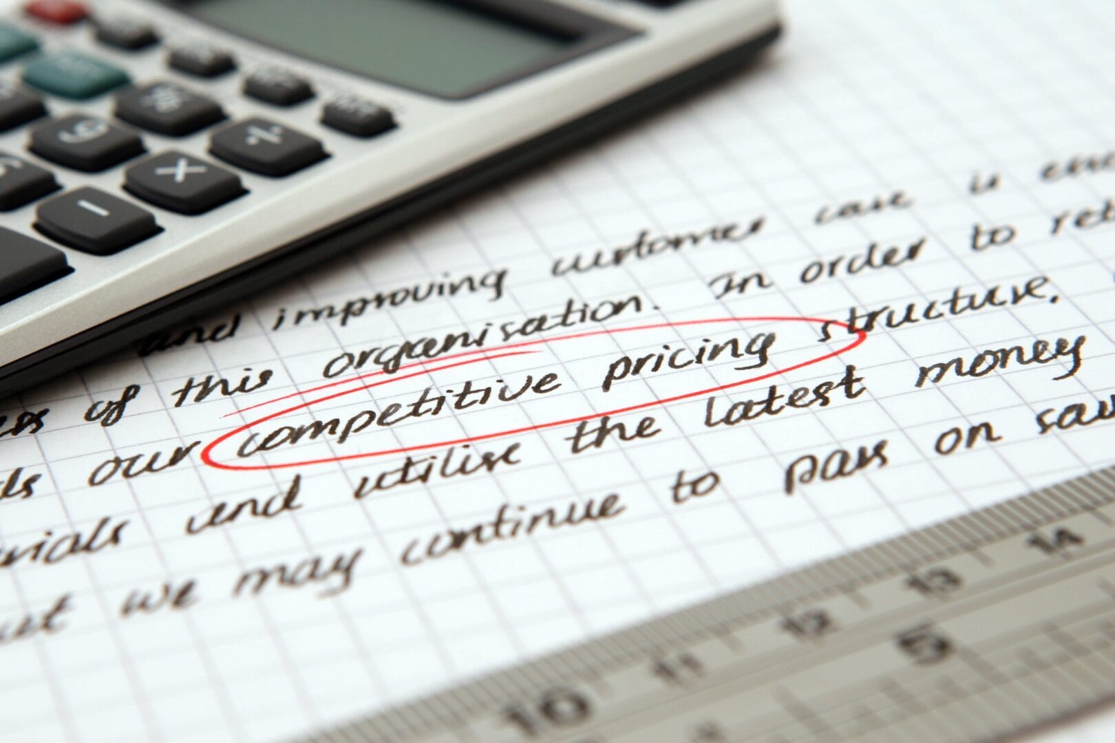 Sheet of paper with the phrase 'competitive pricing' circled in red, with a calculator nearby.