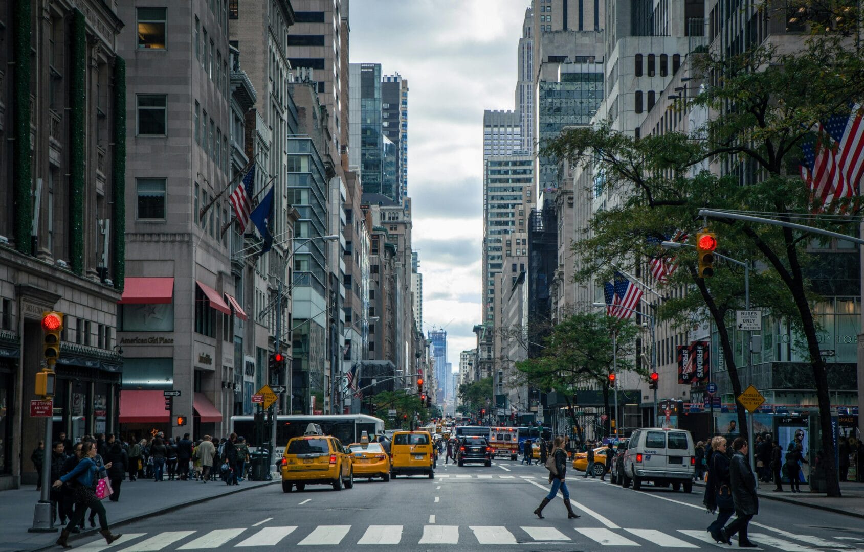 Busy city street with pedestrians, yellow taxis, and tall buildings.
