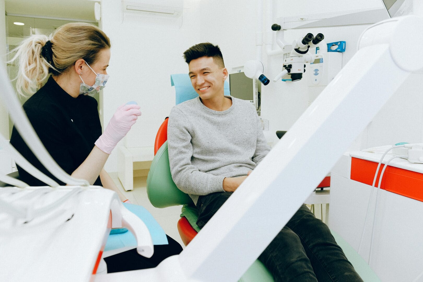 Dental clinic setting with a dentist talking to a patient in the dental chair.