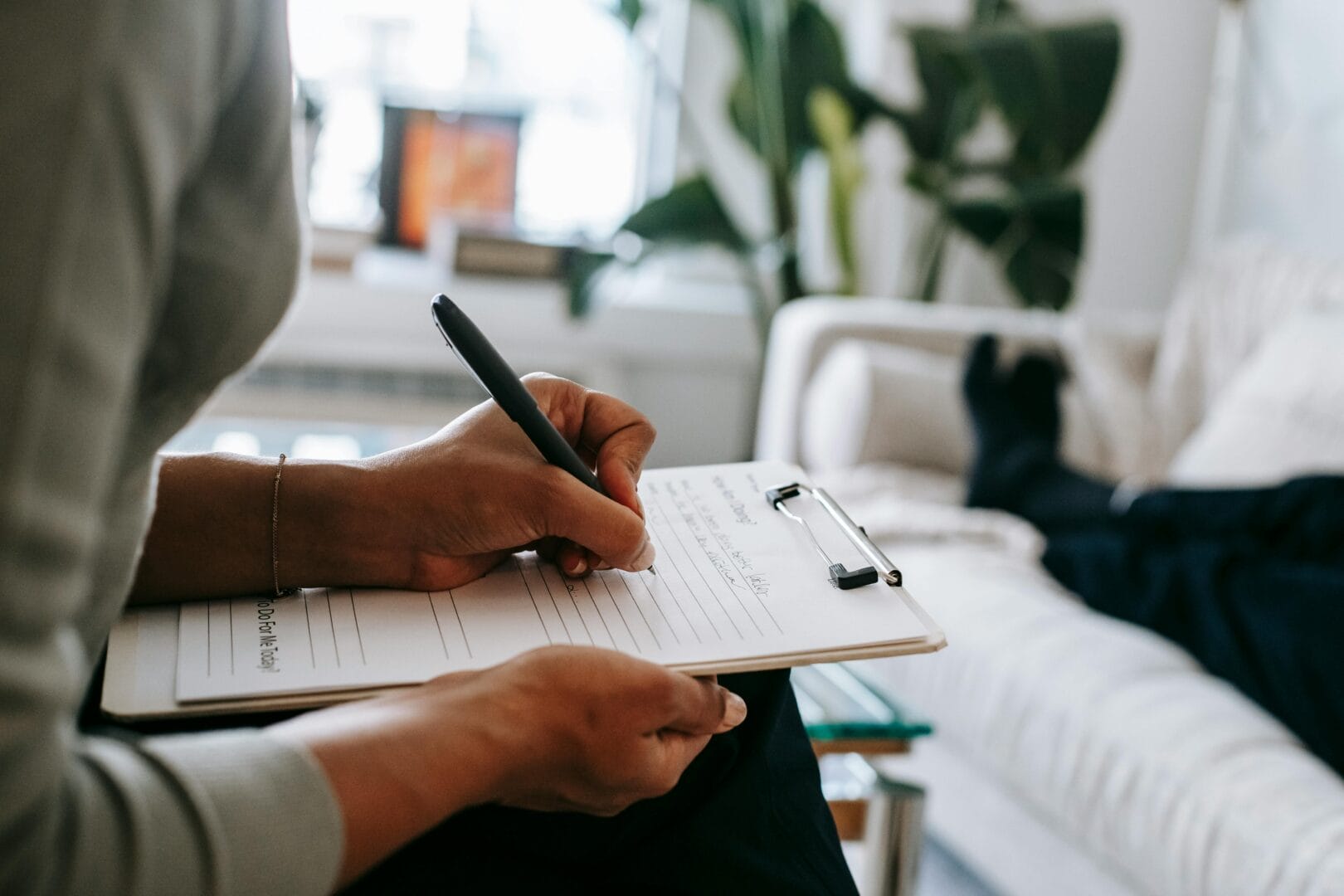 Person writing on a clipboard in a relaxed setting.