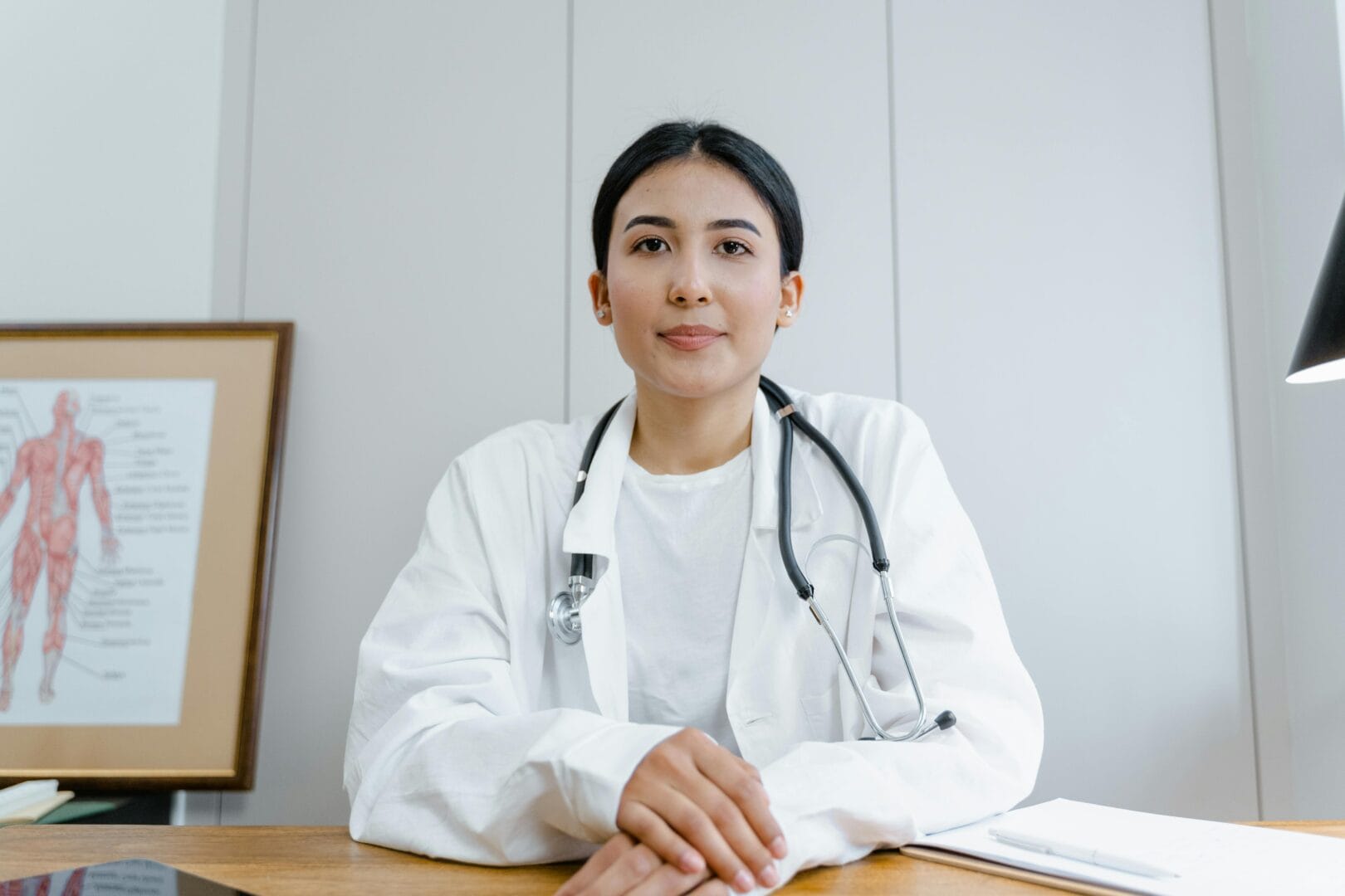 Medical professional sitting at a desk, wearing a stethoscope.