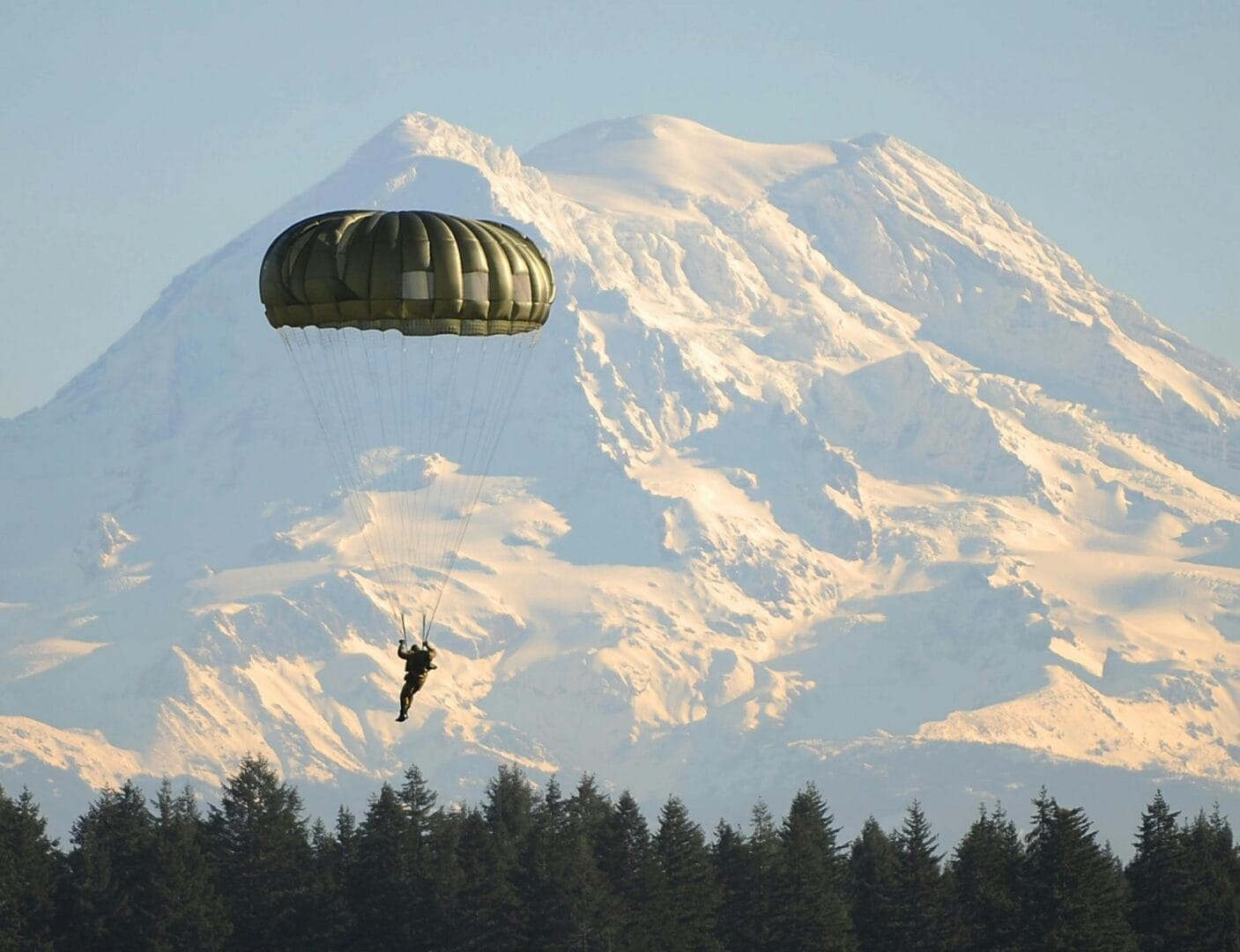 Person parachuting with a mountain in the background.